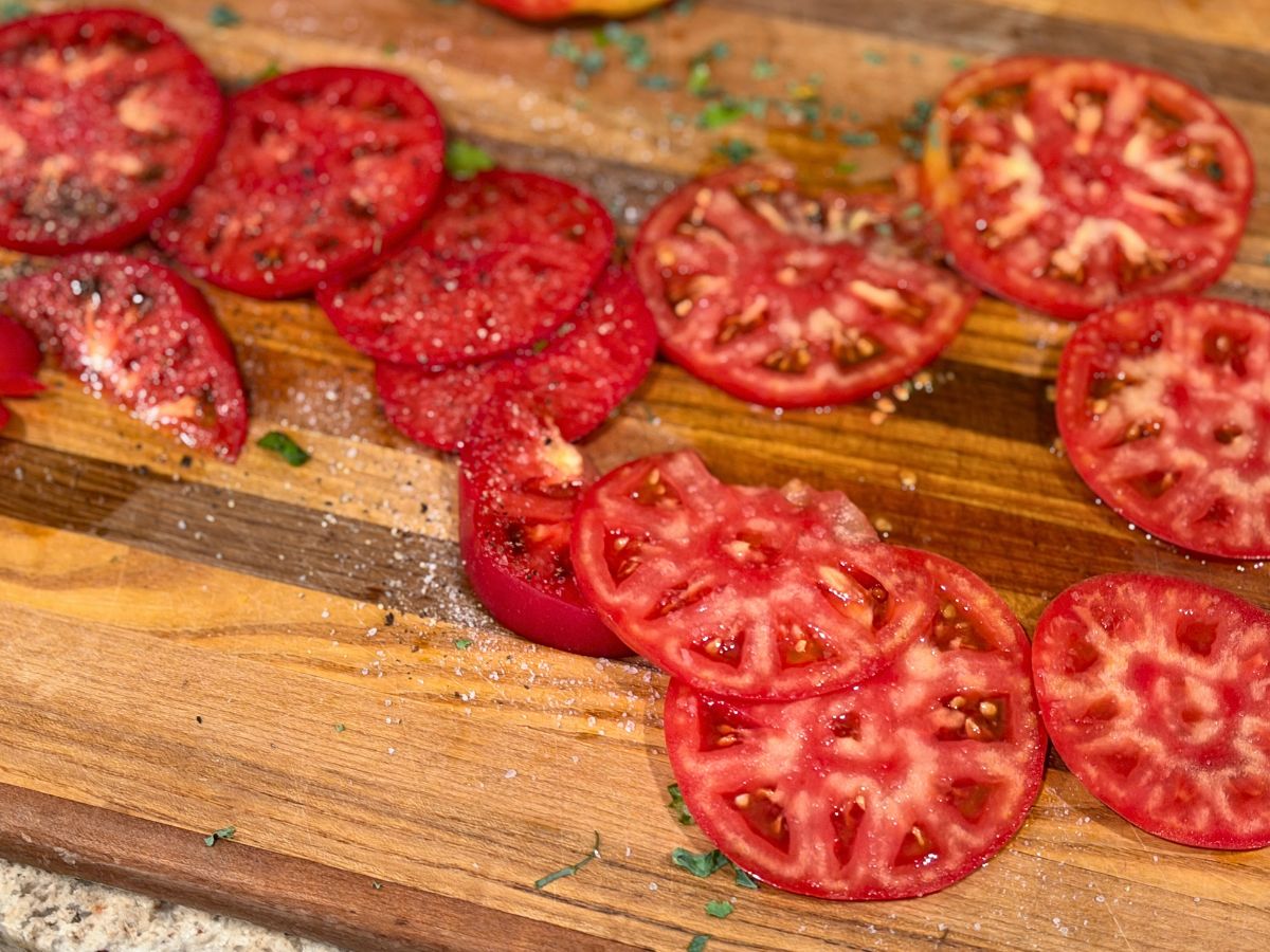 Different varieties of locally grown Central Indiana tomatoes sliced side by side, showing differences in color, flesh, seeds, and texture.
