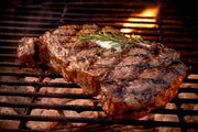 Grilled Grassfed Ribeye steak with rosemary on a barbecue grill