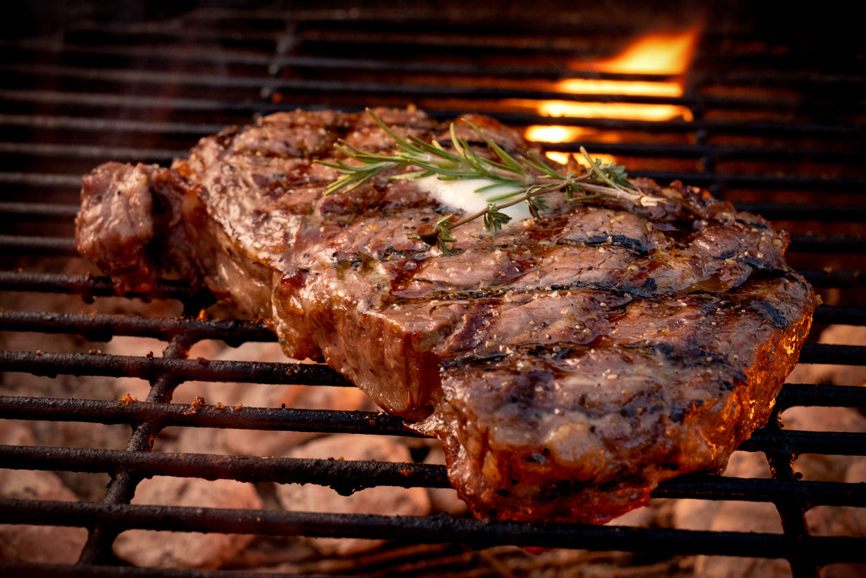 Grilled Grassfed Ribeye steak with rosemary on a barbecue grill