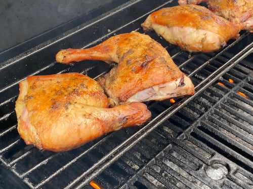 Pasture-raised chicken leg quarters cooking on a grill