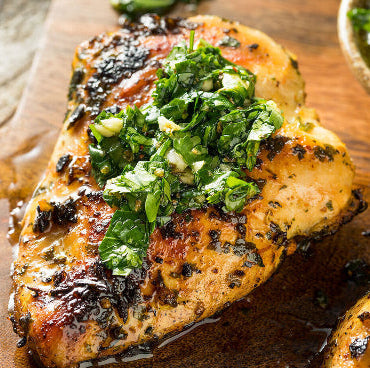 Cooked pasture-raised chicken breast served with green herb sauce