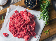 Raw grassfed ground beef on wooden cutting board, sourced from pasture-raised cattle at Tyner Pond Farm in Indiana