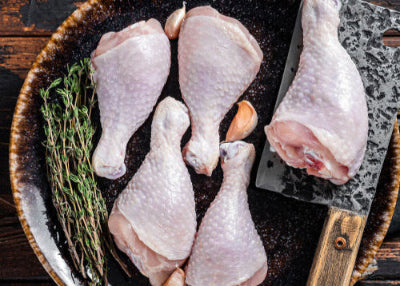 Raw chicken drumsticks arranged on a grill