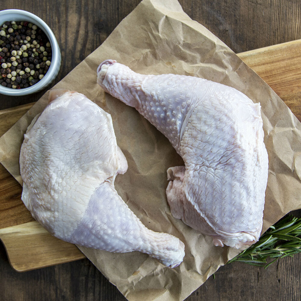 Raw bone-in chicken leg quarters arranged on butcher paper